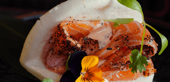 Salmon bao bun with edible flowers.