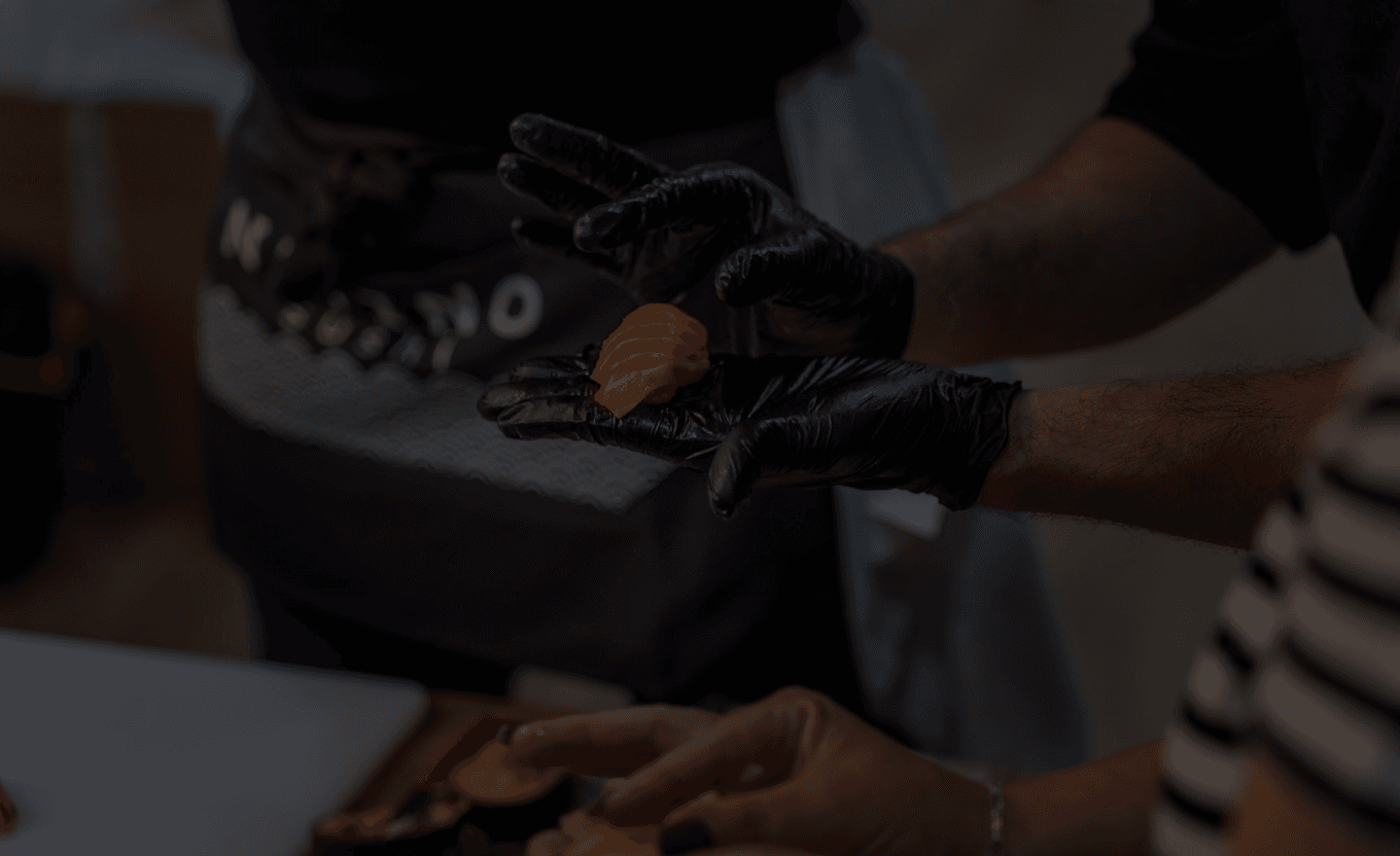A cocktail and premium sushi dishes staged on a dramatic black table.
